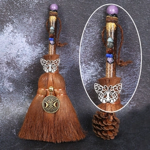 Detail of handmade witch broom with metallic butterfly charm and multicolor crystal stones