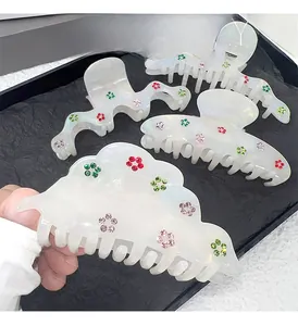 Detail of four-piece pearl white acetate hair claws with colorful rhinestone floral patterns