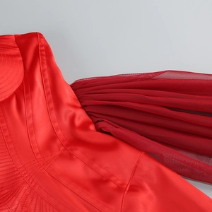Detailed macro view of vibrant red satin fabric and sheer mesh texture on dress shoulder