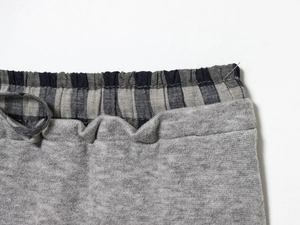 Detail of grey knit waist with adjustable drawstring and blue plaid lining trim