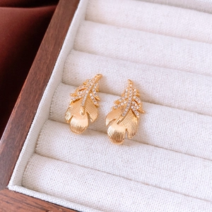 Detail of 18k gold plated feather earrings with small clear zircons in a jewelry box