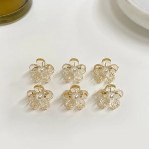 Detail of six amber resin flower hair clips with pearl centers in a 2x3 grid layout