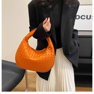 Detail of a bright orange woven hobo bag showing cross-braided leather texture and hobo shape