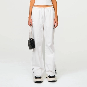 Detail of white cotton flare sweatpants featuring black cross embroidery and drawstring waist
