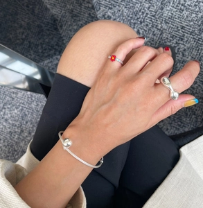 Detail of 925 sterling silver liquid metal ring and red floral beaded ring on model