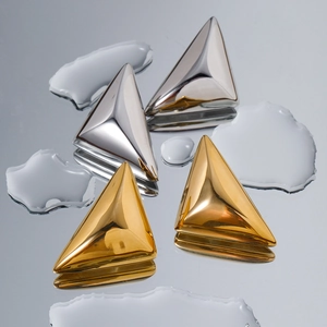 Orecchini a rombo in oro 18k e argento lucido su sfondo d'acqua con riflessi nitidi
