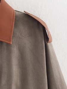 Detail shot of color-block suede jacket showing grey fabric and brown leather collar stitching