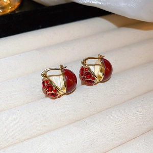 Macro shot of gold-plated square heart earrings featuring sparkling red faceted gems