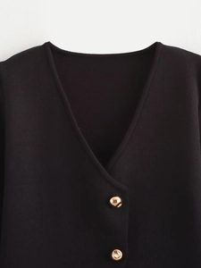 Detail des V-Ausschnitts mit Goldknöpfen und feiner Waffelstrickstruktur auf dem Cardigan