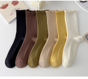 Flat lay of cotton socks with ruffled edges and ribbed texture in six earth tones