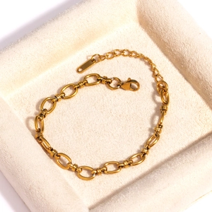Gros plan d'un bracelet gourmette doré avec fermoir mousqueton sur socle velours