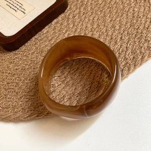 Translucent amber acrylic geometric bangle with vintage marble texture on linen background