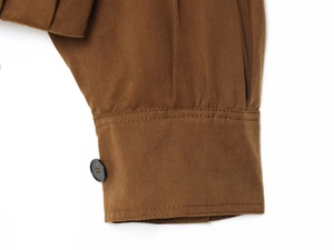 Detailed close-up of brown twill jacket cuff featuring a single black button and neat stitching