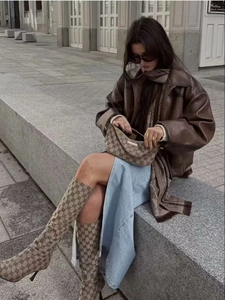Outdoor opname van bruin leren jack gecombineerd met denim rok en luxe print laarzen