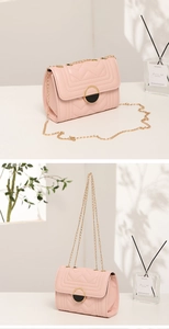 Detail of pink quilted chain bag with gold round lock in a premium home decor setting