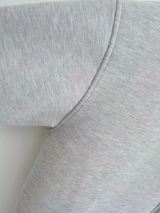 Close-up of armpit stitching and grey knit fabric texture on the hooded sweatshirt