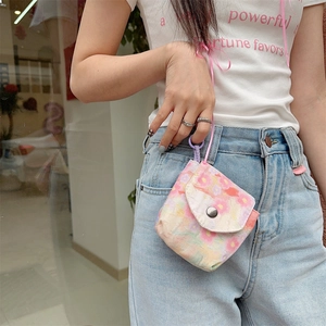 Close-up of small floral canvas pouch with snap closure attached to jeans by pink lanyard