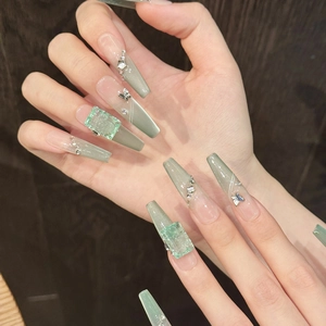 Detail of mint green cat-eye press-on nails with 3D butterfly and crystal accents