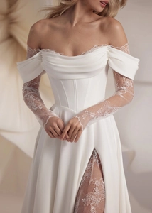 Detail of off-shoulder wedding gown with lace sleeves, corset waist, and high side slit