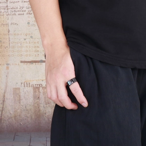 Gros plan détaillé d'une bague large en acier inoxydable noir martelé portée au doigt