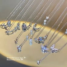 Close-up of sparkling butterfly and star necklaces on a premium golden mirror tray
