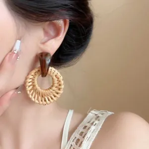 Close-up of bohemian raffia drop earrings with brown resin and natural woven texture