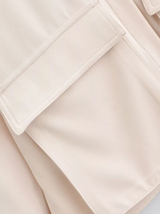 Detailaufnahme der Taschenklappe und Naht an der aprikosenfarbenen Damenbluse