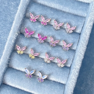 Macro shot of colorful zircon butterfly stud earrings displayed in a blue velvet tray
