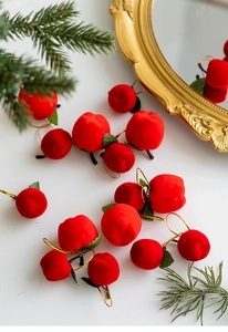 Close-up of red flocked mini apple ornaments with green leaves for Christmas trees