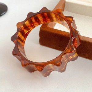 Detailed view of amber resin bangle featuring a stylish wavy design and translucent texture