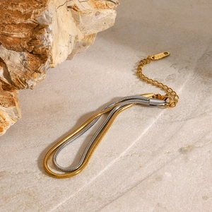 Two-tone gold and silver stainless steel snake chain bracelet on natural stone background