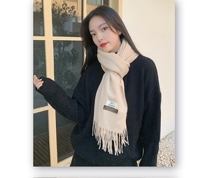 Detail of beige cashmere scarf featuring elegant fringe and a visible SKY logo label