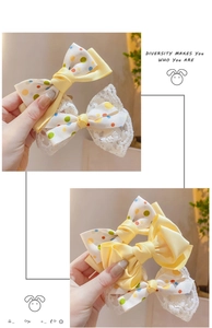 Detail of colorful polka dot bow hair clips with yellow ribbons and lace fabric