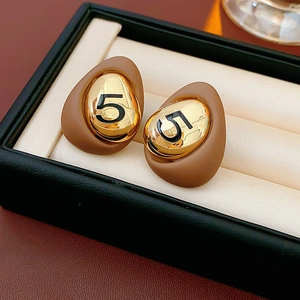 Detailed macro view of gold plated number 5 drop oil earrings in a black jewelry box