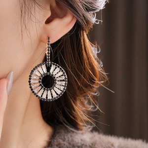 Close-up of gold geometric hoop earrings with blue and clear zircon stones on model