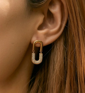 Macro view of gold U-shaped link earrings with pavé zircons on model ear