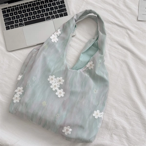 Close-up of mint green tulle tote bag with delicate white floral embroidery on soft fabric