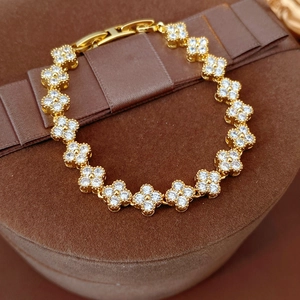 Détail d'un bracelet doré en forme de trèfle orné de pavés de zircons blancs brillants
