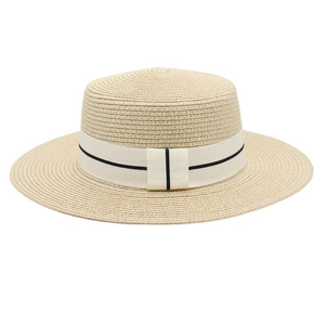 Close-up of beige woven straw bucket hat with white ribbon band and black stripe detail