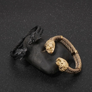 Detailed shot of gold and black wire cable bracelets with lion head ends on a dark stone