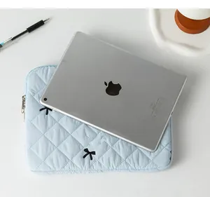 Detailed view of light blue quilted iPad sleeve with embroidered black bows and zipper