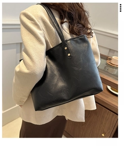 Detail view of black PU leather tote bag with grainy texture and gold rivet accents
