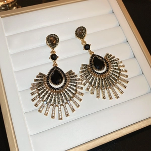Vue détaillée de boucles d'oreilles dorées en éventail avec pierres noires et strass