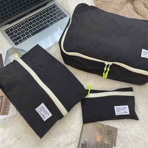 Three-piece black waterproof travel organizers with contrast yellow zippers on white rug