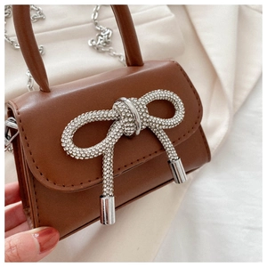 Detailed close-up of dark brown leather mini bag with silver rhinestone bow and chain