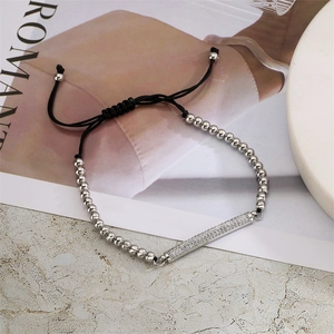 Détail d'un bracelet à billes argentées avec barre de zircons et cordon noir réglable