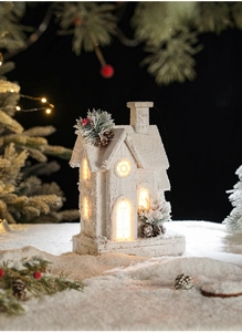 Detail of illuminated wooden Christmas cabin with snow texture and warm LED lights
