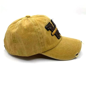 Detail der vintage gewaschenen gelben Baseballkappe mit abgenutzter Krempe und NY-Stickerei