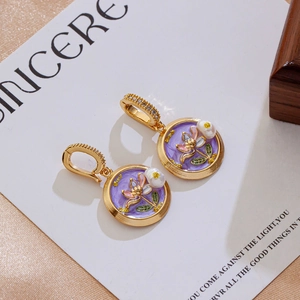 Detail of purple enamel flower earrings with gold plating and cubic zirconia accents