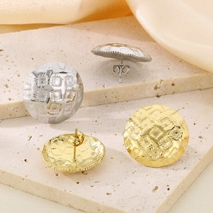 Detail of gold and silver dome stud earrings with hammered metal texture on silk fabric